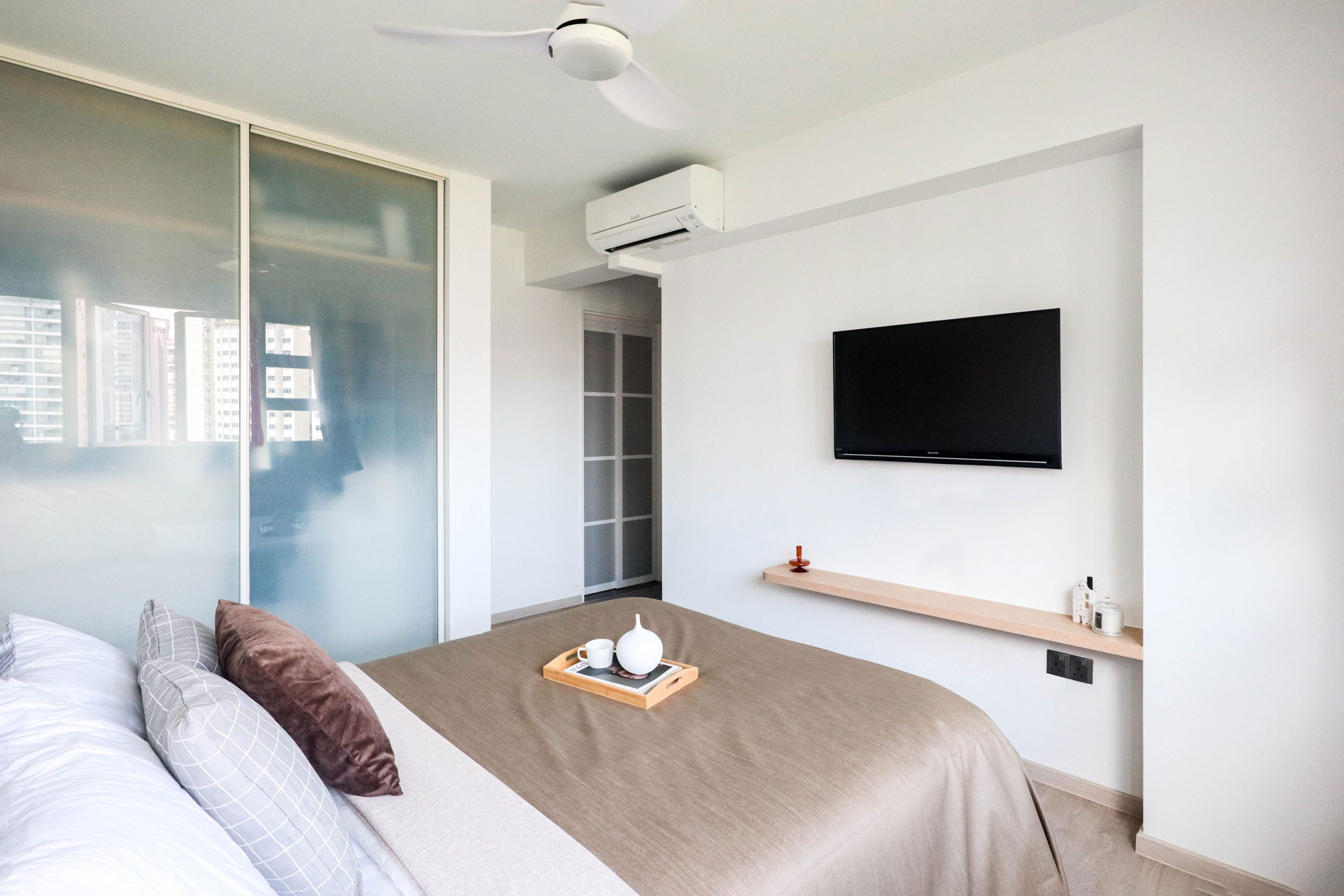 HDB master bedroom with floating tv console and full height custom wardrobe in muji style